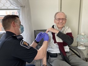 Ottawa paramedic Sébastien Dubé administers a second dose of a COVID-19 vaccine to his grandfather, Yvon Dubé, 88. He had not seen Yvon or his grandmother, Madeleine, in more than a year because of restrictions related to the COVID-19 pandemic.