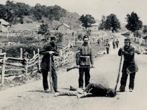 Canadian militia pose next to a dead Fenian killed during an 1870 raid into Quebec.