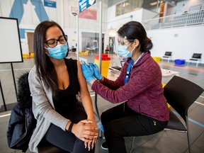 Nurse Mandeep Kaur, right, administers a dose of the Moderna COVID-19 vaccine to Brittany Orantes, health administrator at a vaccination centre, in Brampton, Ont., on Thursday.