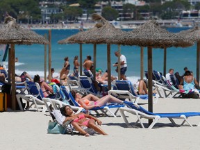 FILE PHOTO: People sunbathe in Magaluf beach, amid the coronavirus disease (COVID-19) outbreak in Palma de Mallorca, Spain.