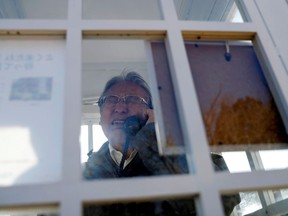 Kazuyoshi Sasaki, 67, who lost his wife, Miwako, in the March 11, 2011 earthquake and tsunami, reacts as he calls his late wife inside Kazo-no-Denwa (the phone of the wind), a phone booth set up for people to call their deceased loved ones, ahead of the 10th anniversary of the disaster, at Bell Gardia Kujira-yama in Otsuchi town, Iwate Prefecture, northern Japan, February 27, 2021.