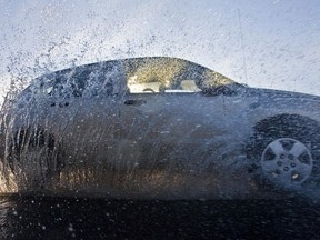 A car makes waves as it drives through a large puddle in Ottawa.