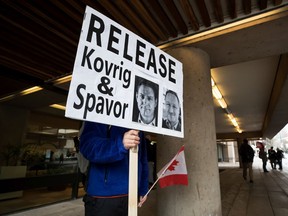 A young man holds a sign bearing photographs of Michael Kovrig and Michael Spavor, who have been detained in China for more than two years.