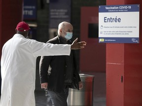 A Montrealer is guided toward the entrance of the Olympic Stadium vaccination centre March 29, 2021, for his COVID-19 vaccine.