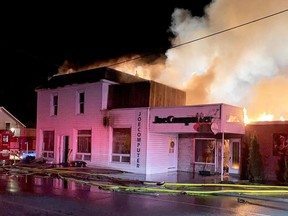 Firefighters battle a blaze that left nine people homeless and destroyed two businesses in Spencerville early Friday.