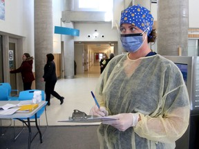 File: A nurse assesses people for possible signs of COVID-19 as they enter Queensway Carleton Hospital's main entrance.
