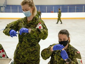 Lt. Samantha O'Keefe, left, and Cpl. Carole-Anne Laroche, both from 1 Canadian Field Hospital, prepare to administer vaccinations to Garrison Petawawa Canadian Armed Forces members.