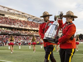 Two RCMP officers carry the Grey Cup on the field at TD Place Arena after the announcement that Ottawa will host the 2017 CFL Grey Cup game at TD Place Arena in Ottawa Sunday, July 31, 2016.