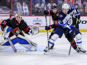 Ottawa Senators defenseman Victor Mete (98) checks Winnipeg Jets center Mark Scheifele (55) in front of goaltender Anton Forsberg (31) during second period NHL action at the Canadian Tire Centre.