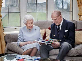 Queen Elizabeth II and Prince Philip, Duke of Edinburgh look at their homemade wedding anniversary card, given to them by their great grandchildren Prince George, Princess Charlotte and Prince Louis, in the Oak Room at Windsor Castle ahead of their 73rd wedding anniversary, on November 17, 2020.