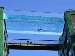 A model swims in a transparent acrylic swimming pool bridge that is fixed between two apartment blocks at Embassy Gardens next to the new US Embassy in south-west London on April 22