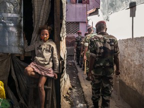 A child sit with her protective mask across her mouth and nose as members of the army patrol the streets of Antananarivo, Madagascar.