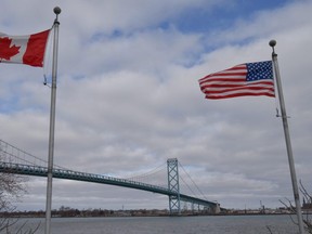 Canadian and American flags fly near the Ambassador Bridge at the Canada-U.S. border crossing in Windsor, Ont. on Saturday, March 21, 2020.