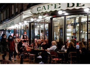 People share drinks at the terrace of the "Cafe de Flore" in Paris on Oct. 26, 2020, prior to a nighttime curfew imposed there as part of measures aimed at curbing the spread of COVID-19.
