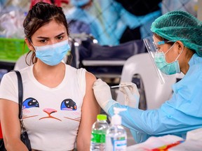 FILE: A health worker administers the CoronaVac vaccine, developed by China's Sinovac firm, to a woman from an at-risk group following a Covid-19 coronavirus cluster traced to entertainment venues, at a makeshift clinic at Saeng Thip sports ground in Bangkok on April 7, 2021.