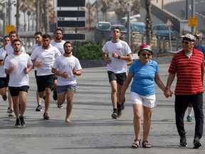 People exercise on a street in the Israeli coastal city of Tel Aviv on April 18, 2021, after authorities announced that face masks for COVID-19 prevention were no longer needed outside.