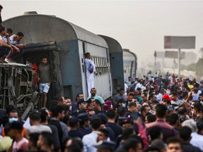 People gather by an overturned train carriage at the scene of a railway accident in the city of Toukh in Egypt's central Nile Delta province of Qalyubiya on April 18, 2021.