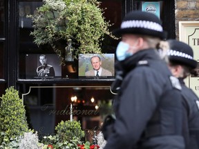 Police officers walk past pictures of Britain's Prince Philip, husband of Queen Elizabeth, who died at the age of 99, in Windsor, near London, Britain April 12, 2021.