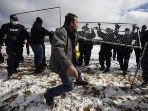 Supporters try to tear down the fence as police struggle with them outside GraceLife Church in Spruce Grove near Edmonton Alta, on Sunday April 11, 2021. The church has been fenced off by police and Alberta Health Services in violation of COVID-19 rules.