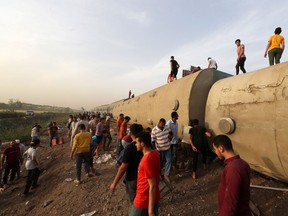 People gather at the site where train carriages derailed in Qalioubia province, north of Cairo, Egypt April 18, 2021.