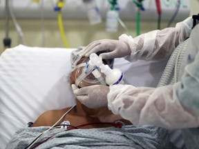 FILE: A medical worker adjusts an oxygen mask on a patient with coronavirus disease.