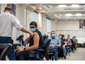 A team at a mobile vaccine clinic administers a dose of the Moderna COVID-19 vaccine.