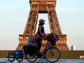 FILE PHOTO: A woman, wearing a mask, rides her bicycle near the Eiffel tower at Trocadero square in Paris.