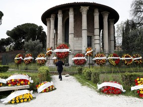 A man in a Rome cemetery carries a funeral wreath with the words "Apologize but they don't let us bury your loved ones" written across it.  Rome's cemeteries are running out of space to store coffins,