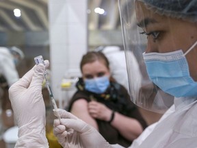 FILE: A medical worker fills a syringe.