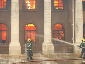 Firefighters battle flames as the library at the University of Cape Town burns after a bushfire broke out on the slopes of Table Mountain in Cape Town, South Africa, April 18, 2021.