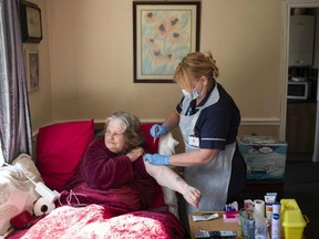 Team leader for housebound vaccinations, Julie Fletcher administers a dose of AstraZeneca/Oxford Covid-19 vaccine to housebound patient Gillian Marriott at her home in Hasland, near Chesterfield, central England on April 14, 2021.