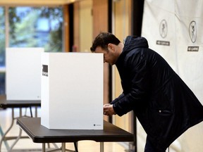 A voters casts their ballot at a polling station in Vancouver, British Columbia, Canada, on Monday, Oct. 21, 2019. Canadian Prime Minister Justin Trudeau appears set to retain power in a close election Monday but lose his parliamentary majority, forcing him to rely on a left-leaning party to survive a second term.