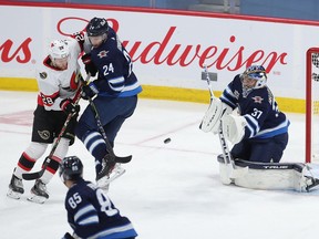 Connor Brown of the Senators deflects the puck past Jets netminder Connor Hellebuyck for a goal in the first period of Saturday's game at Winnipeg. It was Brown's 20th goal of the season.