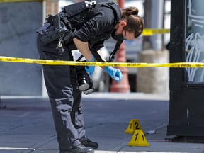 Ottawa Police investigating at Somerset Street West and Cambridge Street North in the Chinatown area of the city. A forensics officer examines a shell casing found on the sidewalk. Thursday, May. 6, 2021.