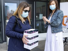 Sarah Parmenter, left, picked up COVID-19 rapid test kits for her business from Ottawa Board of Trade President and CEO Sueling Ching on Friday.