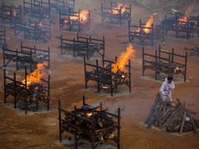 A man wearing PPE (Personal Protective Equipment) performs the last rites of a deceased relative in a disused granite quarry repurposed to cremate the dead due to COVID-19 on April 30, 2021 in Bengaluru, India.