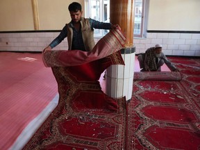 Devotees remove carpets from a mosque after a bomb blast on the outskirts of Kabul on May 14, 2021, that killed at least 12 people, shattering the relative calm of a holiday ceasefire between the warring Taliban and government forces.