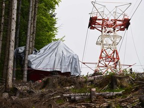 A view shows the cabin's wreckage covered with a tarpaulin next to a pylon on May 26, 2021 on the slopes of the Mottarone peak above Stresa, Piedmont, three days after a cable car crash that killed 14. Photo by MIGUEL MEDINA / AFP