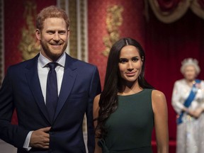 he figures of Britain's Prince Harry and Meghan, Duchess of Sussex, left, are moved from their original positions next to Queen Elizabeth II, Prince Philip and Prince William and Kate, Duchess of Cambridge, at Madame Tussauds in London.