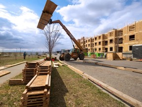 Construction workers stack lumber at a condominium project in Seton on Tuesday, May 11, 2021. Surging lumber prices have created a spike in lumber thefts.