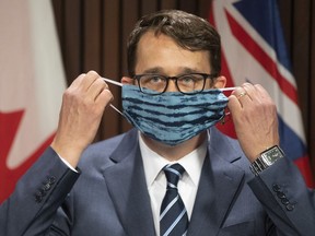 Ontario Labour Minister Monte McNaughton removes his mask as he takes to the podium last week to announce three days of paid sick leave in Ontario.