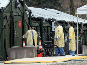 Staff enter the mobile field hospital set up to handle COVID-19 patients at Sunnybrook Hospital in Toronto. After graduating medical school, doctors in Canada must complete practical training of two years for family doctors and five for specialists.