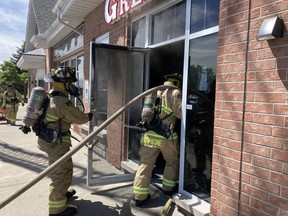 Firefighters at a fire in a commercial plaza on Merivale Road near Central Park Drive Friday.