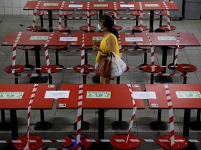 A woman walks between rows of taped up tables at a food centre as dining-in is restricted to curb the coronavirus disease (COVID-19) outbreak in Singapore May 17, 2021.   REUTERS/Edgar Su