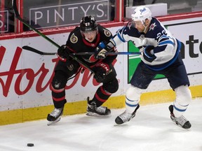 Ottawa Senators centre Shane Pinto (left) battles for the puck with Winnipeg Jets centre Trevor Lewis in the third period at the Canadian Tire Centre, May 3, 2021.