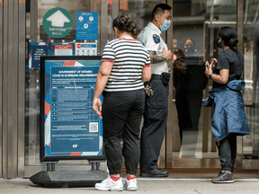 A woman reads COVID-19 protocol signs outside Toronto's Eaton Centre.