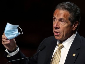 New York Governor Andrew Cuomo holds a protective mask as he speaks while making an announcement at a news conference from the stage at Radio City Music Hall in Manhattan in New York City, New York, U.S., May 17, 2021.