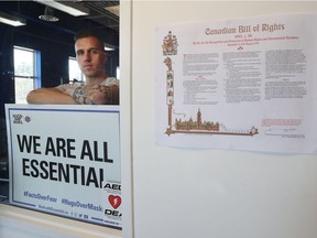 Zachary Boissinot poses with a sign at his A Foot Above Fitness gym in Ottawa Wednesday. Boissinot says he will fight the $4000-plus fines he has received and contends that gyms should be essential businesses because they help keep people healthy during a health crisis.