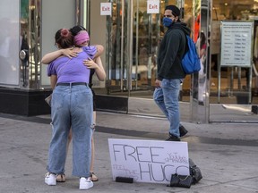 A woman offers "Free Hugs" at the corner of Yonge Street and Dundas Street in Toronto during the Covid 19 pandemic, Sept. 3, 2020.