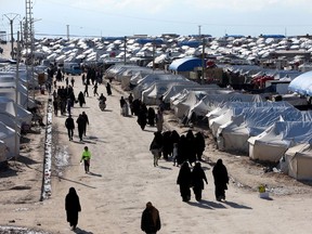 In this file photo, women walk through the al-Hol displacement camp. Canada is in violation of international law by leaving its citizens and their children in such camps.